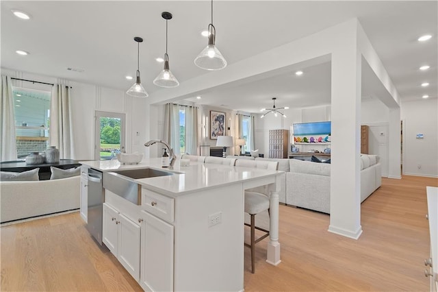 kitchen with pendant lighting, white cabinetry, light hardwood / wood-style flooring, and an island with sink