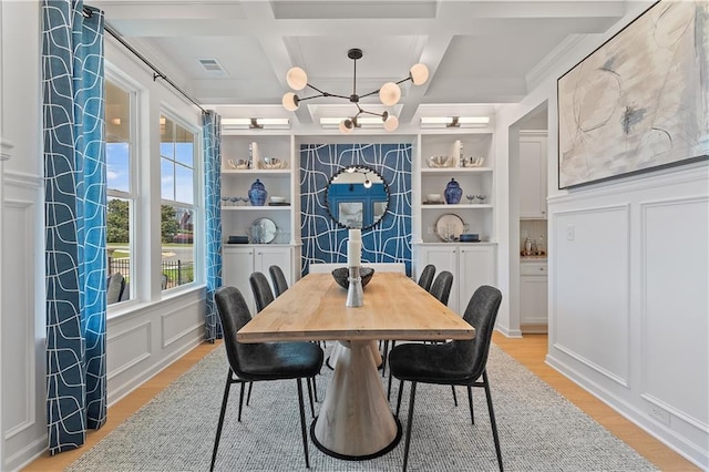 dining room featuring built in shelves, a chandelier, coffered ceiling, and light hardwood / wood-style flooring