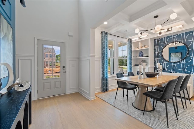 dining room featuring light hardwood / wood-style flooring, built in features, beamed ceiling, and coffered ceiling