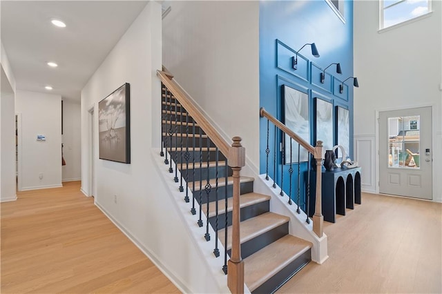 stairway with a towering ceiling and hardwood / wood-style flooring