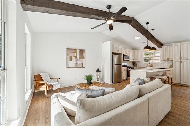 living room with lofted ceiling with beams, ceiling fan, and light hardwood / wood-style floors