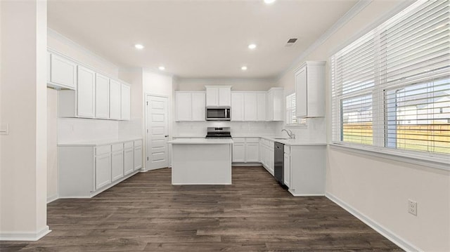 kitchen with appliances with stainless steel finishes, tasteful backsplash, a center island, dark hardwood / wood-style floors, and white cabinetry