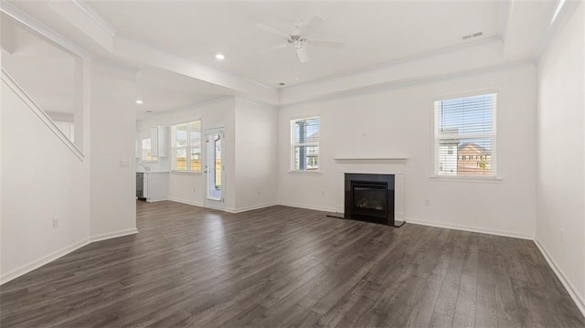 unfurnished living room featuring dark hardwood / wood-style flooring, ceiling fan, a raised ceiling, and ornamental molding