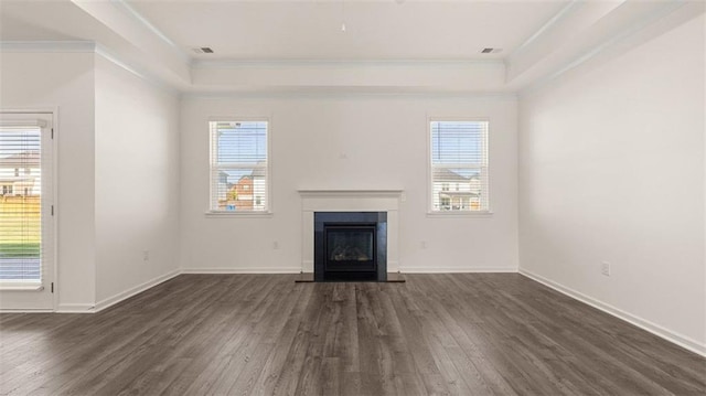 unfurnished living room featuring a tray ceiling, plenty of natural light, dark hardwood / wood-style floors, and ornamental molding