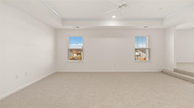 spare room featuring a raised ceiling, ceiling fan, and carpet floors