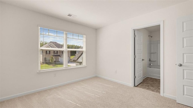 unfurnished bedroom with light colored carpet, ensuite bath, and a spacious closet