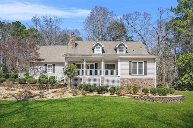 new england style home featuring stone siding, a porch, a chimney, and a front lawn