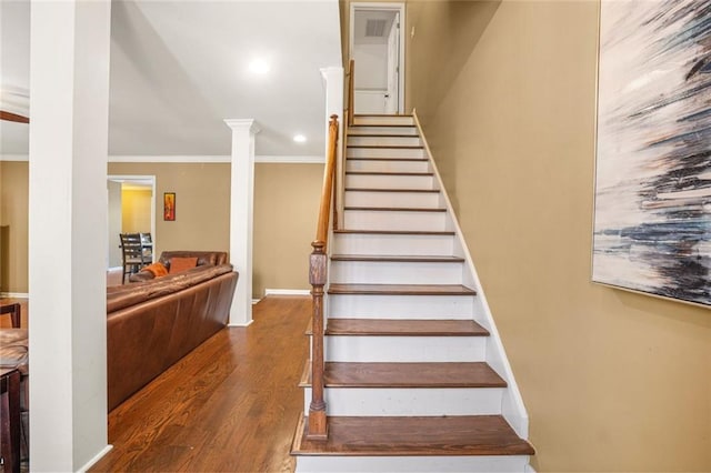 staircase with wood finished floors, recessed lighting, crown molding, baseboards, and ornate columns