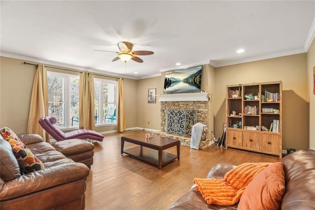 living area with baseboards, a fireplace, wood finished floors, and crown molding