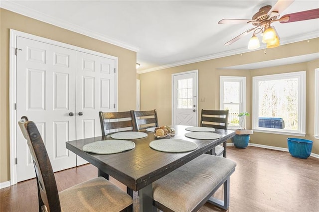 dining room with a ceiling fan, crown molding, wood finished floors, and baseboards