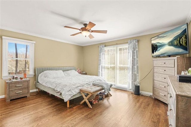 bedroom with a ceiling fan, crown molding, wood finished floors, and baseboards