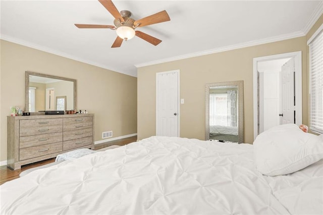 bedroom featuring wood finished floors, baseboards, visible vents, ceiling fan, and crown molding