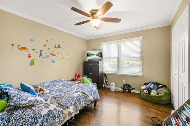 bedroom featuring crown molding, ceiling fan, baseboards, wood finished floors, and a closet