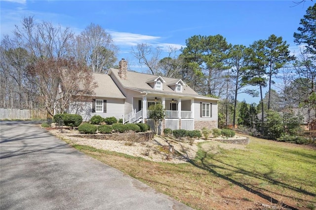 cape cod-style house featuring a chimney, a porch, ceiling fan, and a front yard