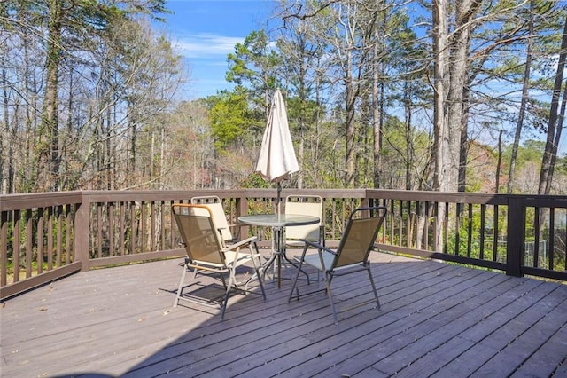 deck with outdoor dining area and a view of trees