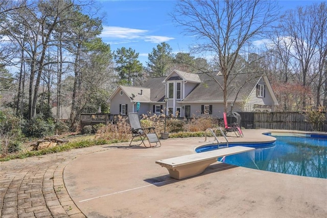 view of swimming pool with a diving board, a patio area, a fenced in pool, and fence