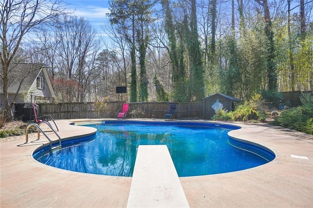 view of swimming pool with an outbuilding, a fenced in pool, a fenced backyard, a diving board, and a patio area