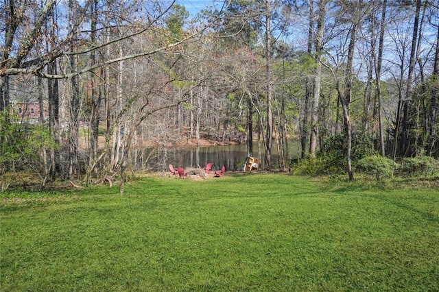 view of yard with a wooded view and a water view