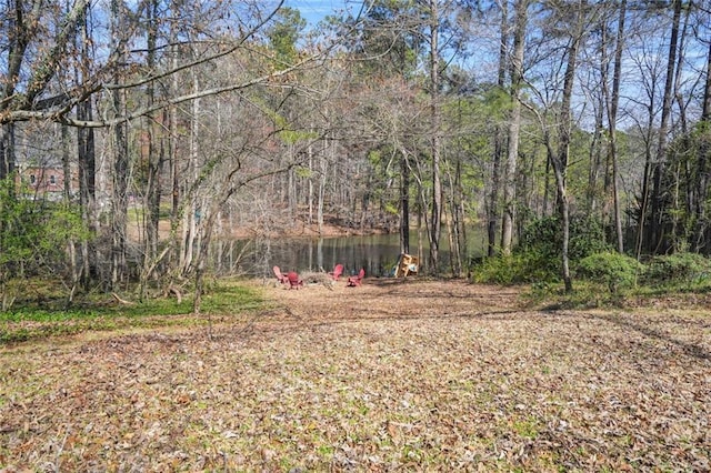 view of yard with a wooded view and a water view