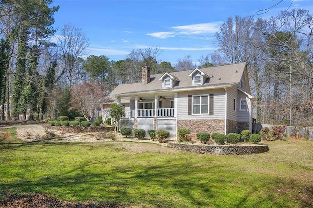 view of home's exterior with ceiling fan, a porch, a chimney, a yard, and stone siding