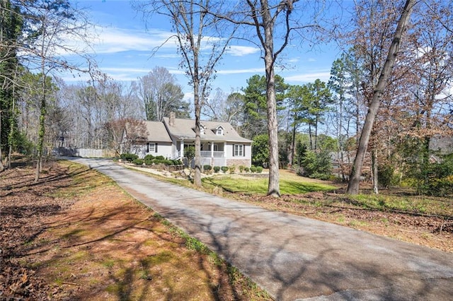 view of front of property with driveway, a chimney, and a front yard