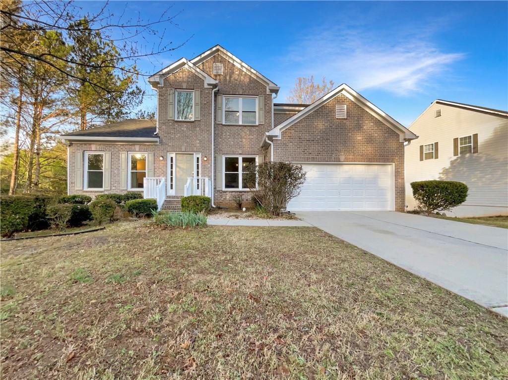 traditional-style home featuring a front yard, brick siding, concrete driveway, and a garage