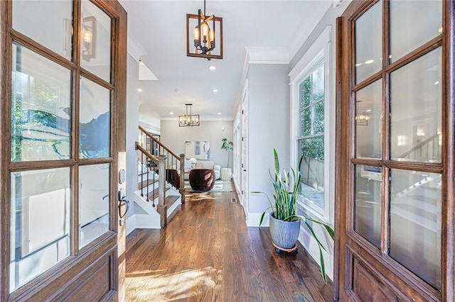 foyer featuring dark hardwood / wood-style floors, french doors, crown molding, and an inviting chandelier