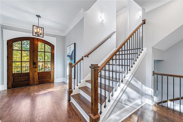 foyer with dark hardwood / wood-style flooring, crown molding, french doors, and a notable chandelier