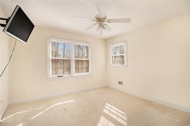 carpeted empty room featuring ceiling fan, a textured ceiling, and a healthy amount of sunlight