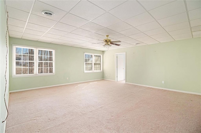 carpeted empty room with ceiling fan and a drop ceiling