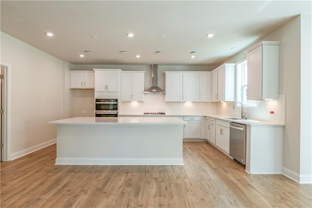 kitchen featuring white cabinetry, appliances with stainless steel finishes, wall chimney exhaust hood, and a kitchen island