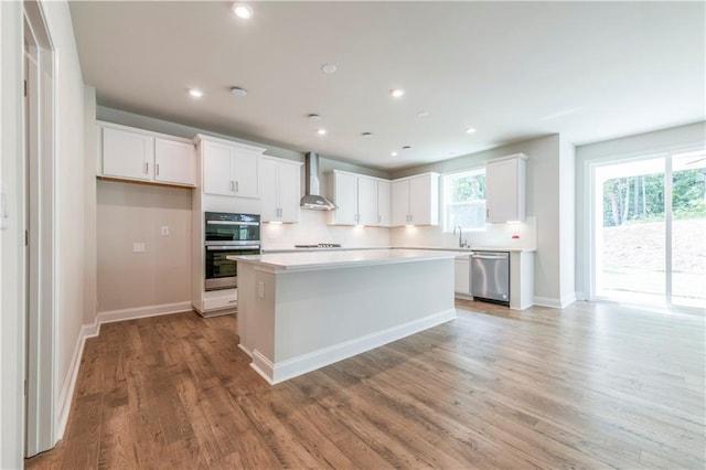 kitchen featuring white cabinetry, wall chimney range hood, a center island, and stainless steel appliances