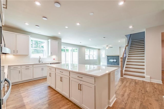 kitchen featuring sink, a kitchen island, white cabinetry, and light hardwood / wood-style flooring