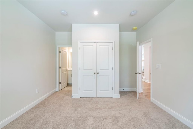 unfurnished bedroom featuring light colored carpet and a closet