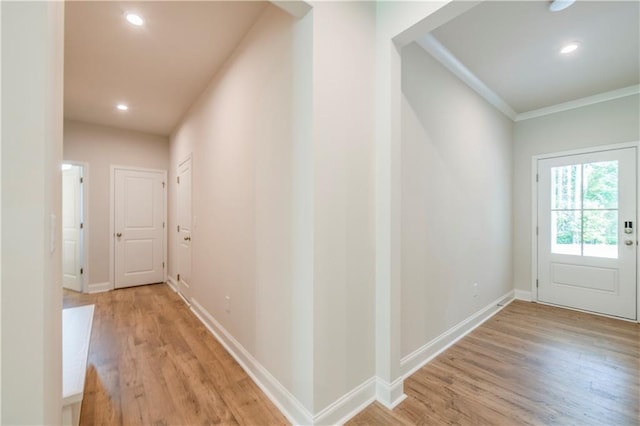 hall with light hardwood / wood-style flooring and crown molding