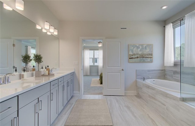 bathroom with vanity, a wealth of natural light, and tiled tub