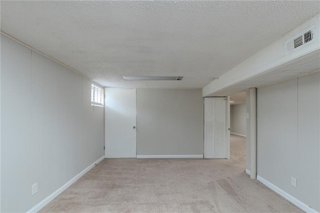 basement featuring light colored carpet and a textured ceiling