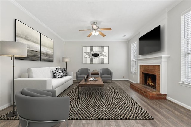 living area with ornamental molding, a brick fireplace, ceiling fan, and wood finished floors