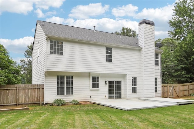 back of property featuring a fenced backyard, a chimney, a lawn, and a deck