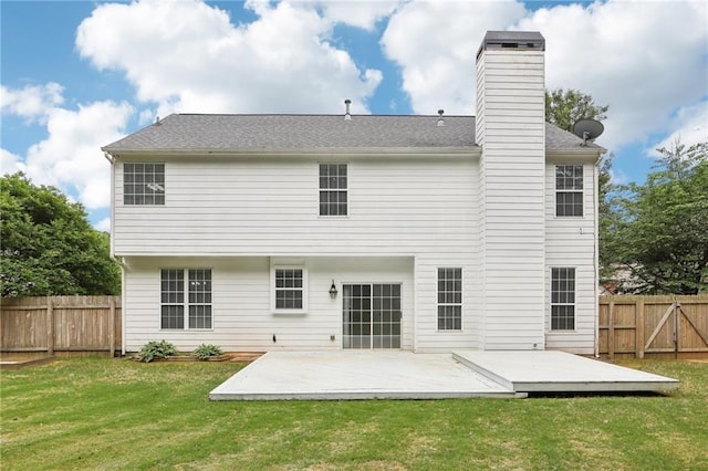 rear view of house featuring a wooden deck, a fenced backyard, a chimney, a lawn, and a patio