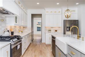 kitchen with gas range, glass insert cabinets, a kitchen island with sink, built in microwave, and a sink