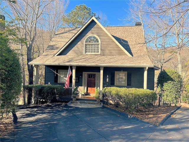 view of front of house featuring a porch, a shingled roof, and a chimney