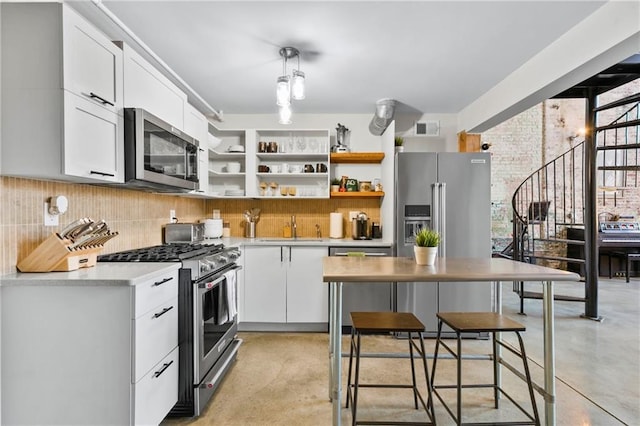 kitchen featuring decorative light fixtures, white cabinetry, tasteful backsplash, high end appliances, and sink