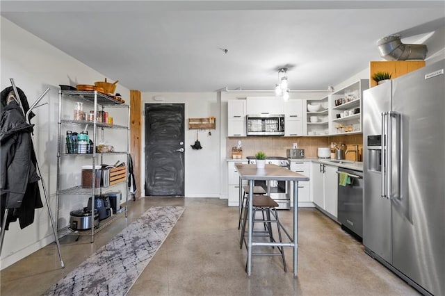 kitchen featuring a kitchen bar, tasteful backsplash, white cabinets, sink, and stainless steel appliances