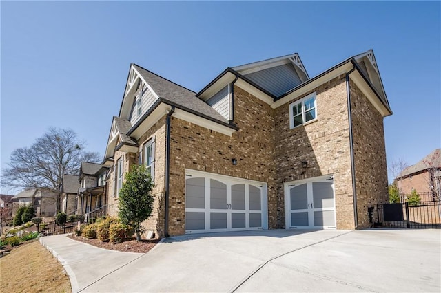 view of home's exterior featuring brick siding, an attached garage, concrete driveway, and fence