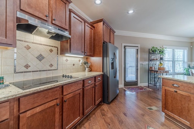 kitchen featuring black electric stovetop, stainless steel fridge with ice dispenser, dark wood finished floors, under cabinet range hood, and ornamental molding