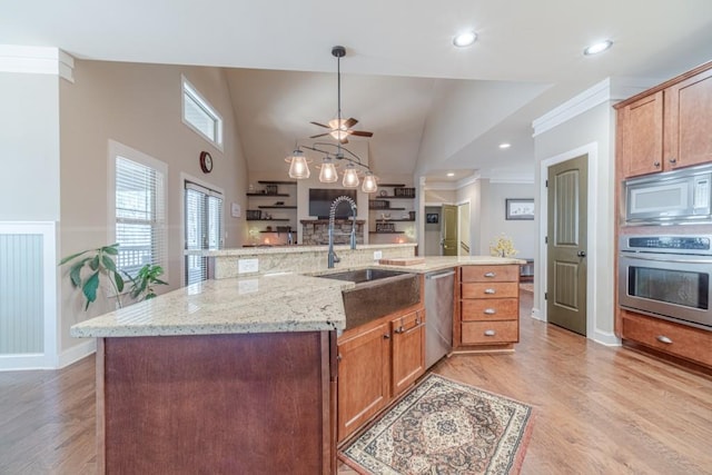 kitchen with pendant lighting, light stone countertops, a sink, light wood finished floors, and appliances with stainless steel finishes