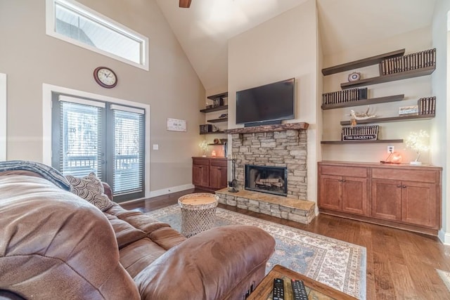 living area with ceiling fan, a fireplace, high vaulted ceiling, baseboards, and wood finished floors