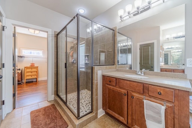 bathroom with baseboards, a shower stall, tile patterned flooring, and vanity