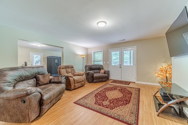 living room featuring visible vents, baseboards, wood finished floors, and a wealth of natural light